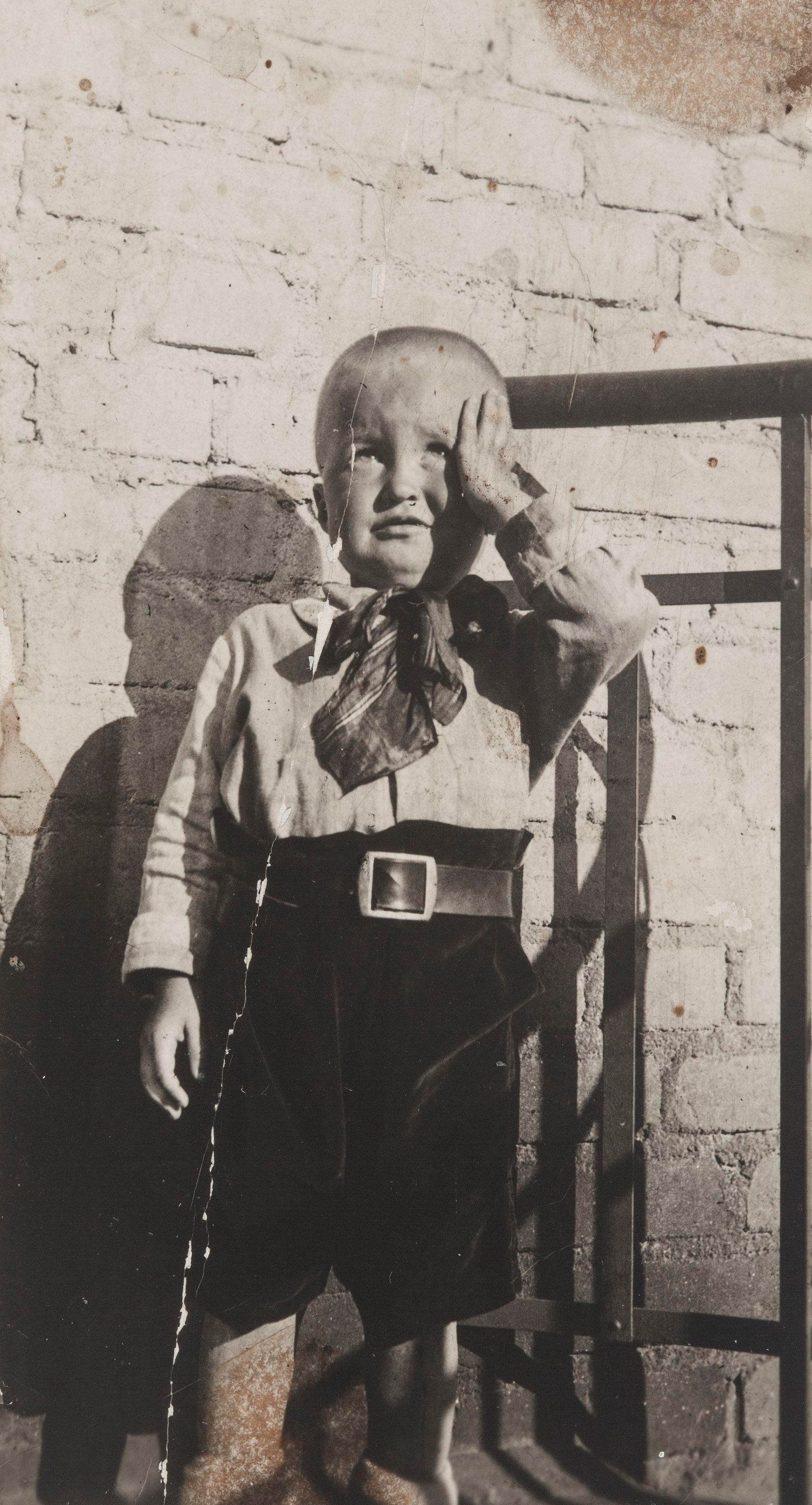 Pieni poika seisomassa tiiliseinän edustalla. Kuvassa todennäköisesti Pentti Niemelä, joka tuli vanhempiensa Leo ja Saara Niemelän kanssa Neuvosto-Karjalaan 1930-luvun alussa. Pentti menehtyi lapsena Nevdubstroilla, jossa hänen vanhempansa olivat töissä rakennustyömaalla. SKS KRA, Niemelä-perheen arkisto. CC BY-NC-ND 4.0
