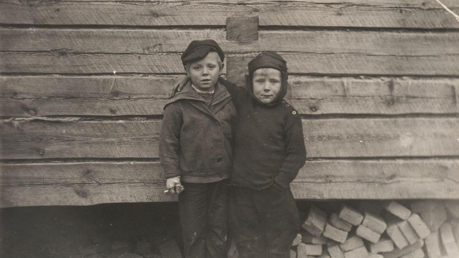 Jouko Männikkö naapurinpojan kanssa seisomassa puurakennuksen edessä. Kuva Neuvosto-Karjalasta vuodelta 1935. Kuva SKS KRA, Männikkö-perheen arkisto. CC BY 4.0