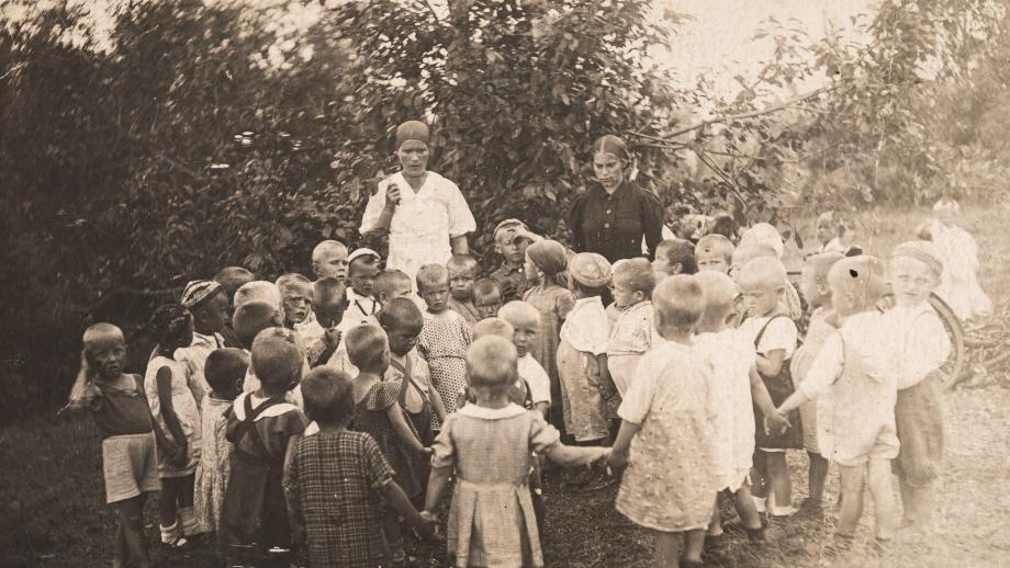 Ryhmäkuva lapsista ja kahdesta lastentarhan opettajasta pihalla. Kuva on otettu Sverdlovskin alueella Lobvassa noin vuonna 1942. SKS KRA, Niemelä-perheen arkisto. CC BY 4.0