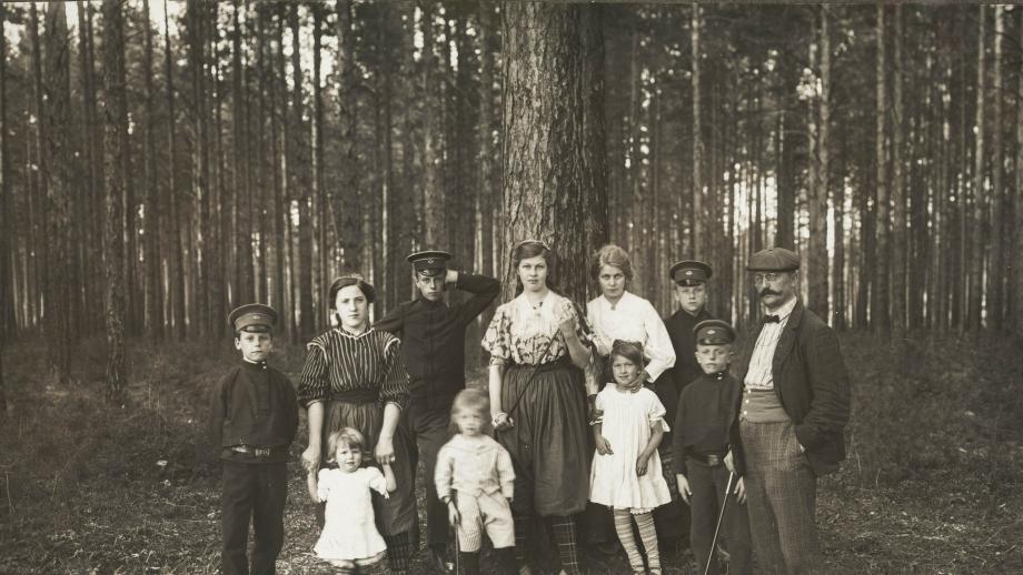 Kokokuva yksitoistahenkisestä seurueesta mäntymetsässä. Kuva otettu Uralilla Baženovon kylässä 1900-luvun alussa. Kuva SKS KRA, Sverberg-perheen arkisto. CC BY 4.0